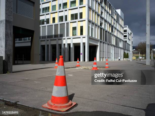 traffic cone in front of a residential building with dramatic sky in springtime - schild schweiz stock-fotos und bilder