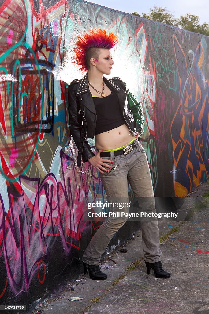 Young punk woman leaning on wall