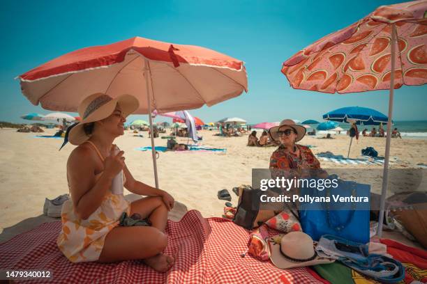 tourists enjoying the beach under the beach umbrella - sun hat stock pictures, royalty-free photos & images