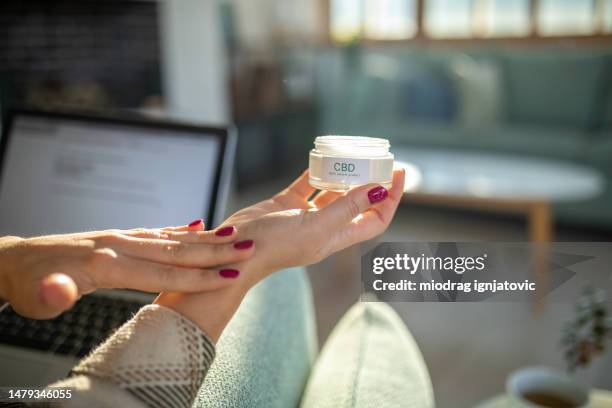 woman applying cream with cbd - painkiller stock pictures, royalty-free photos & images