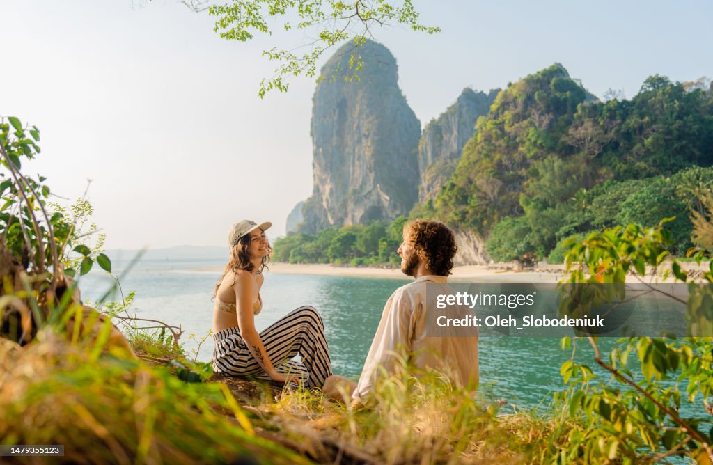 Donna e uomo che si siedono sulla scogliera sullo sfondo della baia di Railey