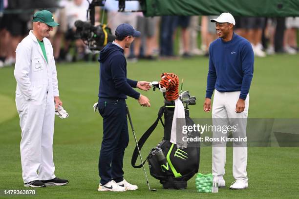 Rory McIlroy of Northern Ireland laughs with Tiger Woods of the United States in the practice area prior to the 2023 Masters Tournament at Augusta...