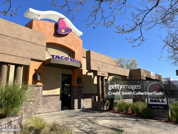 Taco Bell drive-thru with open daily hours and surrounding plants, located in a city landscape with a clear sky above, Walnut Creek, California,...