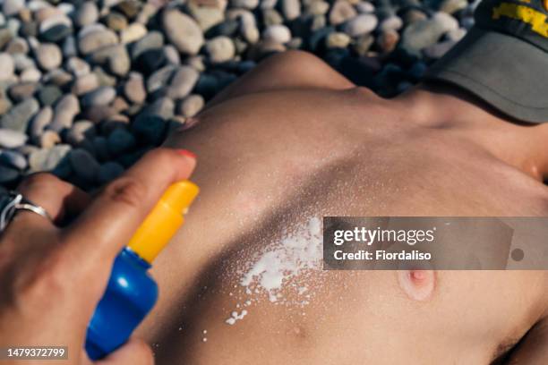 teenager lying on the sea beach sunbathing on pebbles - hot boy body stock-fotos und bilder