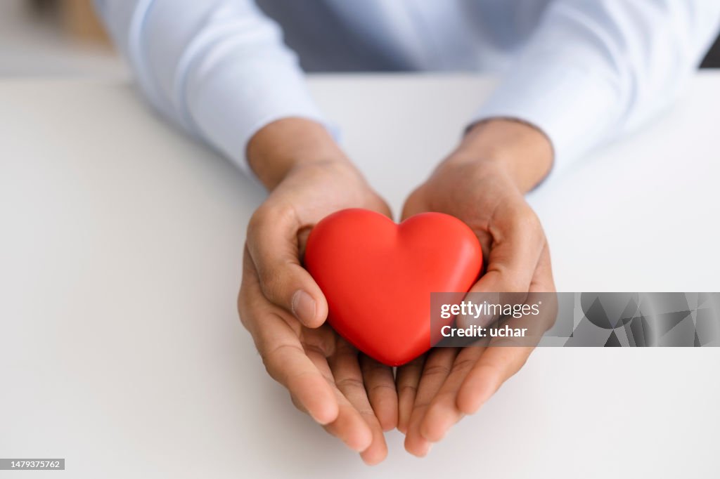 Uomo d'affari irriconoscibile che tiene la forma del cuore