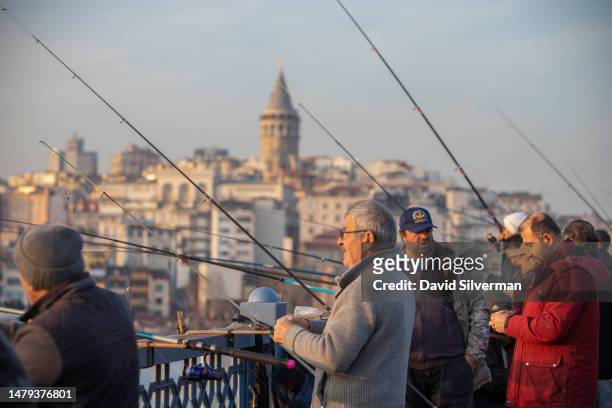 Turkish men supplement their income by fishing off Galata Bridge, which spans the Golden Horn waterway, with the iconic Galata Tower in the...
