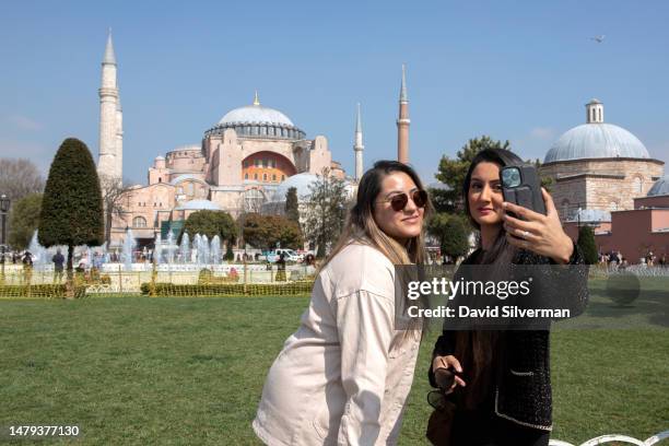 Turkish women pose for a selfie in front of the Hagia Sophia mosque on March 20, 2023 in Istanbul, Turkey. The twin factors of the country's...