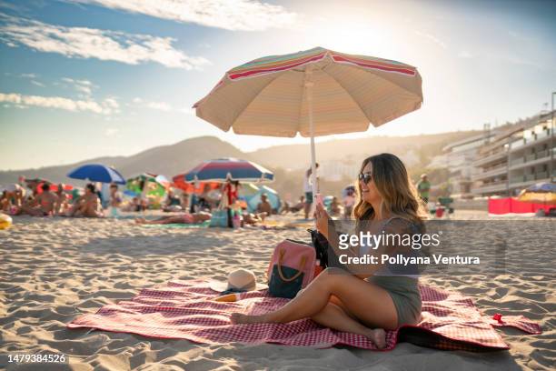 mujer en videollamada en la playa - sombrilla fotografías e imágenes de stock