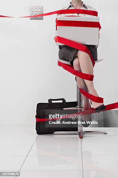 seated businesswoman tangled in red tape - administrative professional stock pictures, royalty-free photos & images