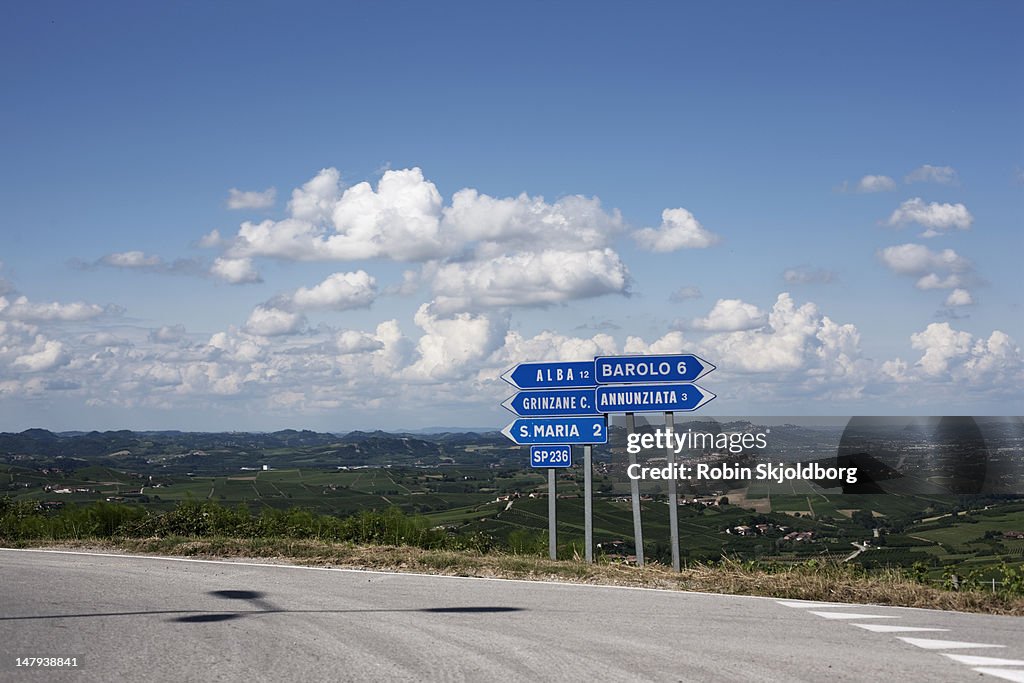 Road signs in front of blue sky with clouds.