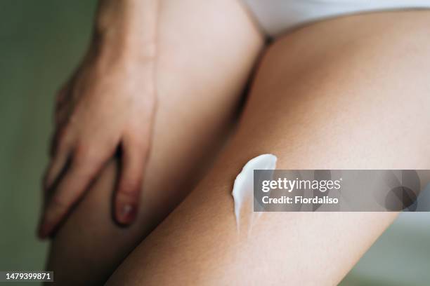white oily body cream or anti-cellulite scrub, smear of gel on female leg - oily skin stock pictures, royalty-free photos & images