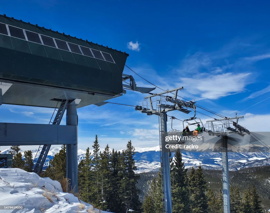 Skier and snowboarder nearing the top of a ski lift, Keystone ski resort Colorado.