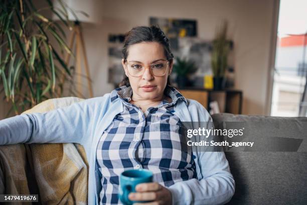 mujer sentada en el sofá - una mujer de mediana edad solamente fotografías e imágenes de stock