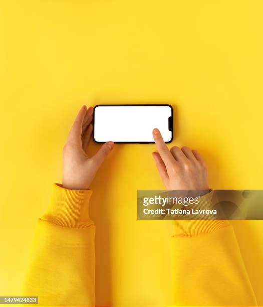 female hand in yellow hoodie using smart phone with white screen. minimalistic composition with copy space.  goals setting, shopping list, finance, mobile gaming, economy, analysis concept - infolist stock-fotos und bilder