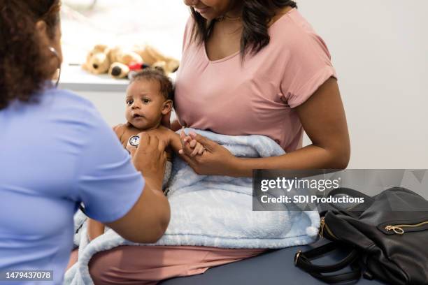 mom holds patient baby as doctor listens to his heart - boy exam stock pictures, royalty-free photos & images