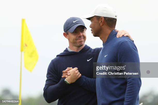 Rory McIlroy of Northern Ireland shakes hands with Tiger Woods of the United States on the 18th green after they completed a practice round prior to...