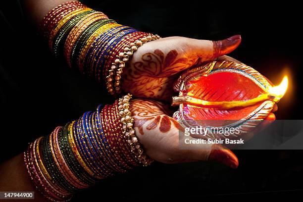 woman with lit earthen lamp at diwali festival - henna hands photos et images de collection