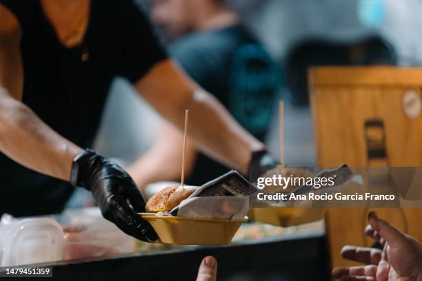 a foodtruck worker woman serving a some burgers to a customer - furgone ambulante foto e immagini stock