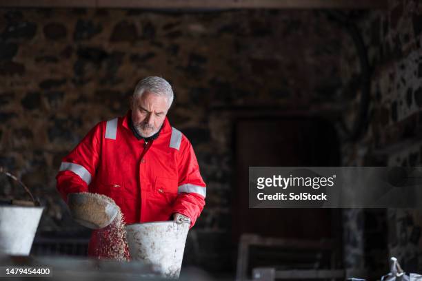 farmer preparing feed in the barn - daily bucket stock pictures, royalty-free photos & images