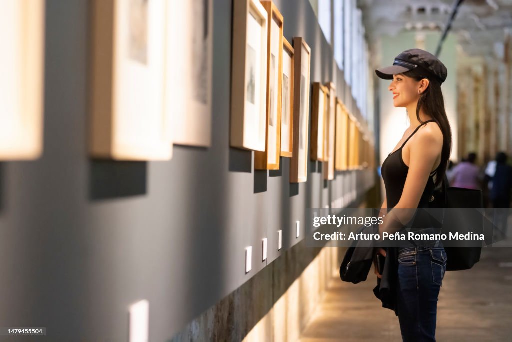 Happy young woman appreciating works of art in museum