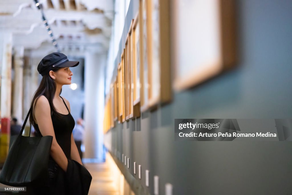 Junge Frau begutachtet Kunstwerke im Museum