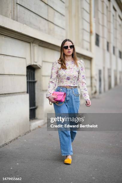 Maria Rosaria Rizzo wears a gold long chain with large cross pendant necklace, a beige with purple and pink tie and dye print pattern long sleeves /...