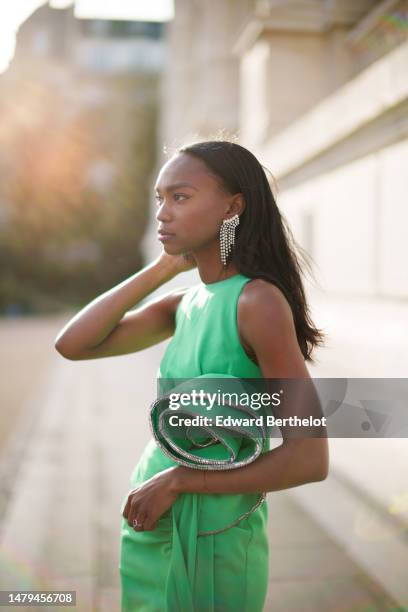 Emilie Joseph wears crystals fringed pendant earrings, a green halter-neck / sleeveless / embroidered large flower on the waist / slit long tube...