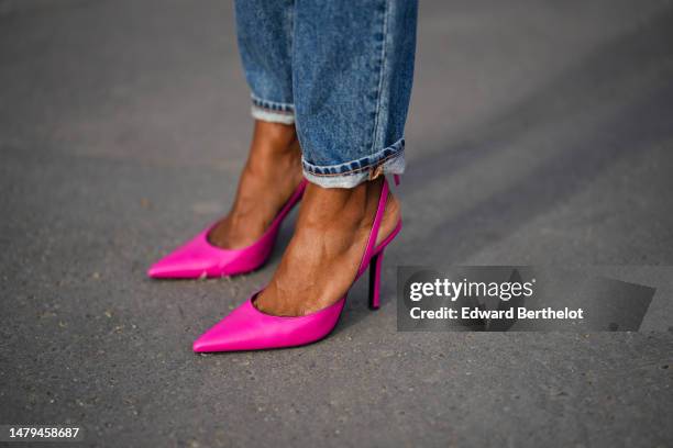 Emilie Joseph wears blue faded denim with black leather yoke cigarette pants, neon pink shiny leather pointed pumps heels shoes, during a street...