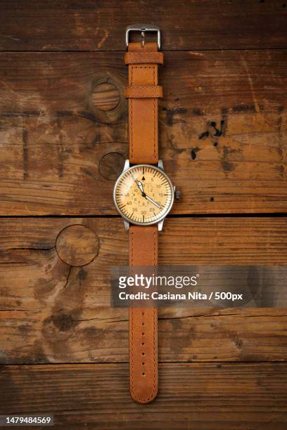 analog wrist watch with brown dial and brown strap on wooden table,romania - classic leather photos et images de collection