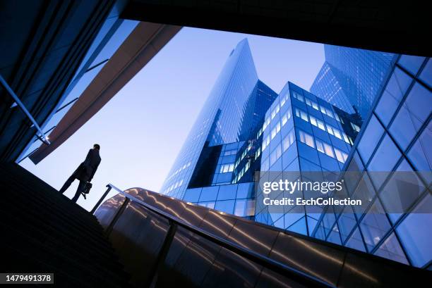 businessman on top of stairs at modern business district - neue wege gehen stock-fotos und bilder
