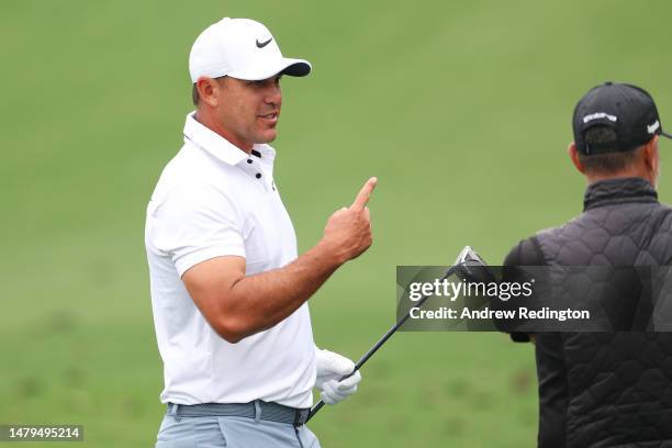 Brooks Koepka of the United States talks with swing coach Claude Harmon III on the practice area prior to the 2023 Masters Tournament at Augusta...