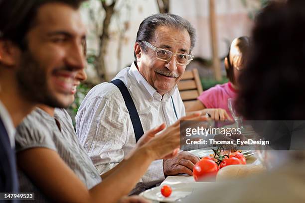 orgoglioso italiano nonno pranzando con la famiglia - gesturing foto e immagini stock