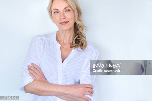 attractive mature woman looking strong and confident and relaxing and looking at the camera. - oudere vrouwen stockfoto's en -beelden