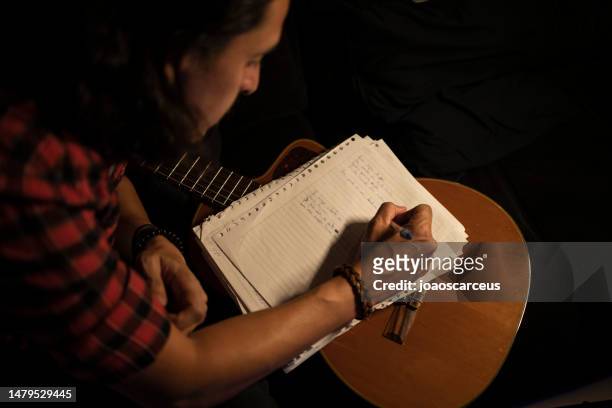 hombre cantando, tocando la guitarra y escribiendo canciones en el estudio de grabación - autor de canciones fotografías e imágenes de stock