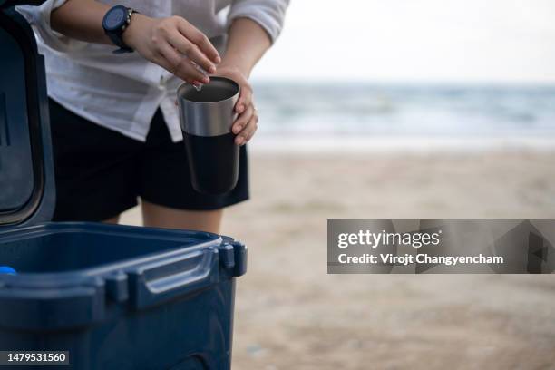 hands take ice from cooler at the beach - ice bucket stock-fotos und bilder