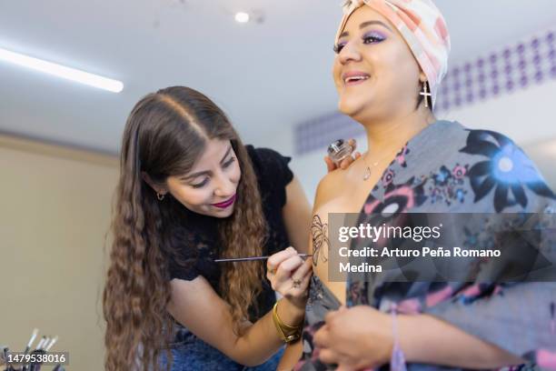 maquilladora haciendo maquillaje conmemorativo en la cicatriz mamaria de una mujer con cáncer de mama - female body painting fotografías e imágenes de stock