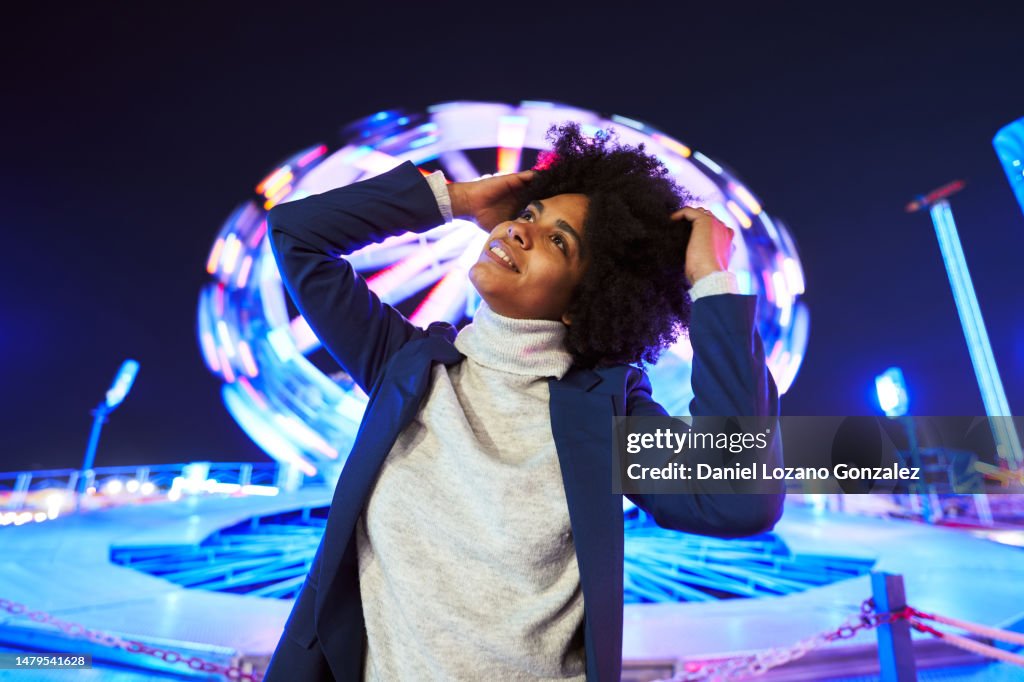 African woman posing in front of a ferris wheel