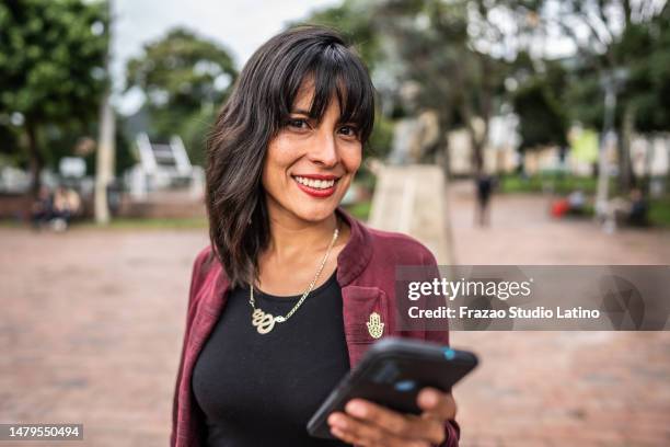 portrait of a mid adult woman using mobile phone outdoors - columbian stock pictures, royalty-free photos & images
