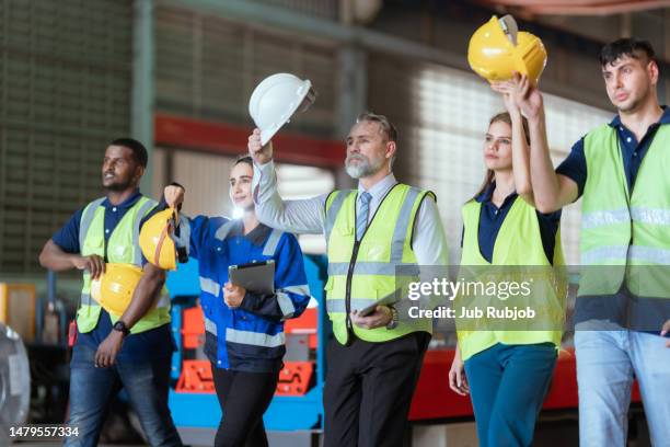 a team of engineers and maintenance workers are walking out after finishing work in a metal sheet factory in a warehouse. - employee safety stock pictures, royalty-free photos & images