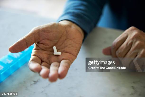 close up of senior man's hand holding pills - taking medication stockfoto's en -beelden