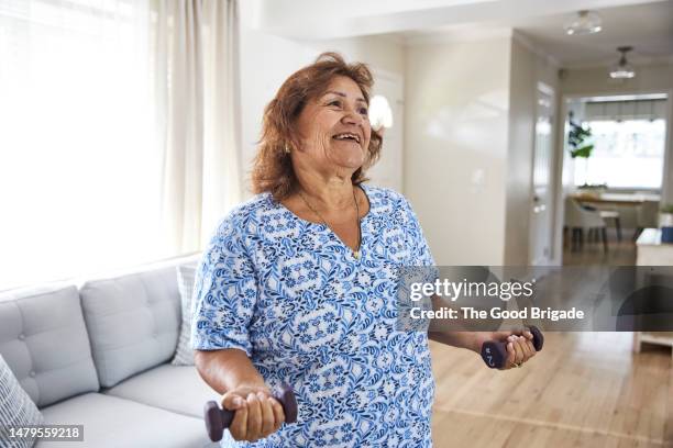 senior woman lifting dumbbells at home - hand weight stock pictures, royalty-free photos & images