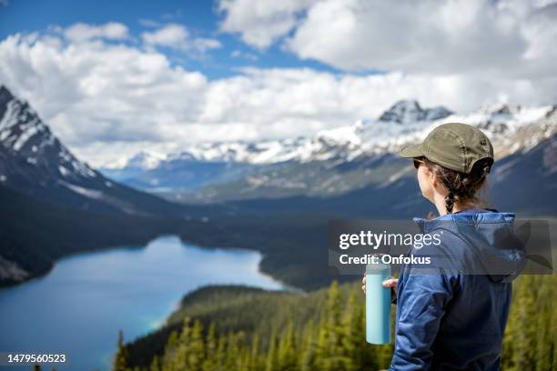 young woman looking at the view of peyto lake in banff national park, alberta, canada - peytomeer stockfoto's en -beelden