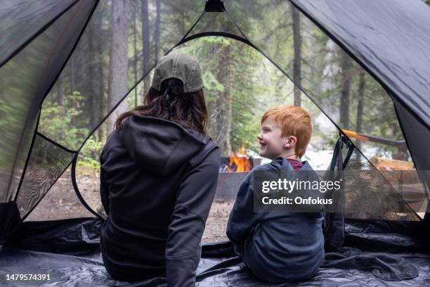 mutter und sohn sitzen in einem zelt auf einem campingplatz in der nähe von campfire, yoho national park, bc, kanada - milestone stock-fotos und bilder