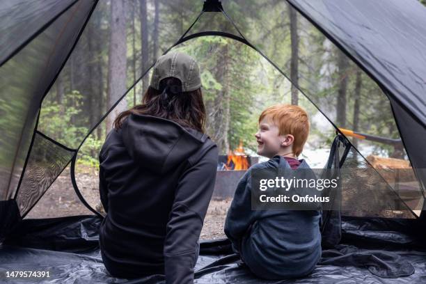 mother and son sitting inside a tent at camping site close to campfire, yoho national park, bc, canada - yoho national park stock pictures, royalty-free photos & images