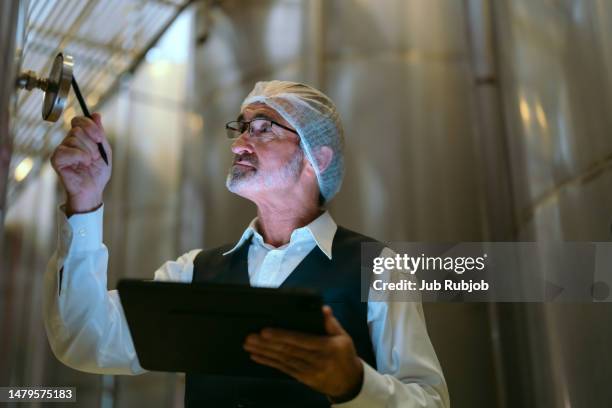 businessman standing using laptop inspecting a small wine cella - chef smelling food stock-fotos und bilder