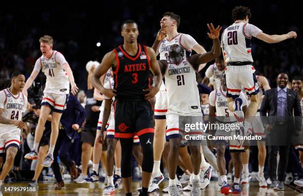 Micah Parrish of the San Diego State Aztecs reacts as Adama Sanogo of the Connecticut Huskies and teammates celebrate after Connecticut defeats San...