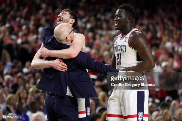 Alex Karaban and Adama Sanogo of the Connecticut Huskies celebrate with head coach Dan Hurley after defeating the San Diego State Aztecs 76-59 during...