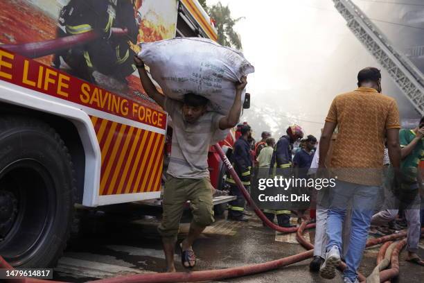 Businessman seen removing their goods from old place and moving to secure locations as a fire erupts at the Bangabazar market shopping complex on...