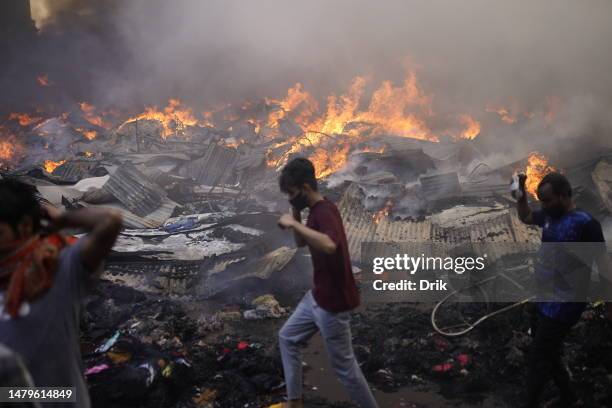 Businessman seen crossing the blaze as a fire erupts at the Bangabazar market shopping complex on April 4, 2023 in Dhaka, Bangladesh. Bangabazar, one...