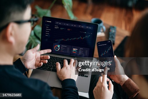 Young Asian couple managing finance and investment online, analyzing stock market trades with mobile app on laptop and smartphone. Making financial plans. Banking and finance, investment, financial trading, mobile banking concept